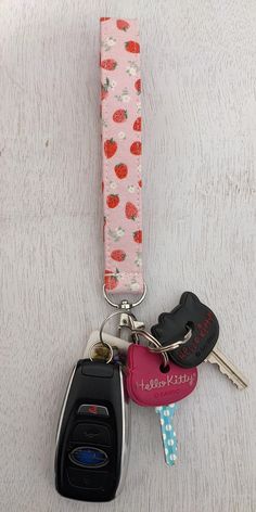 two car keys are attached to a pink keychain with strawberrys on it