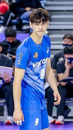 a young man standing on top of a basketball court wearing a blue uniform and white shoes