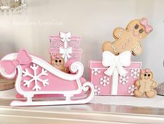 some pink and white gingerbread christmas decorations on a shelf next to a teddy bear in a sleigh