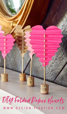 pink heart shaped paper lanterns are lined up on a shelf