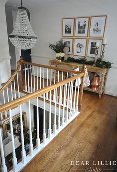 a white staircase with wooden handrails and framed pictures on the wall above it