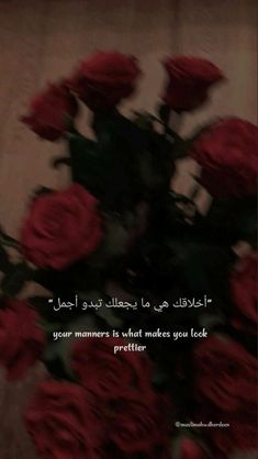 a bouquet of red roses sitting on top of a table next to a quote written in arabic