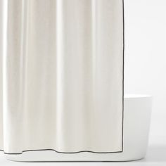 a white shower curtain with black trim on the edge and bottom line, in front of a bathtub