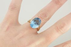 Although bold, his vintage cocktail ring is perfectly balanced in size and width, and so not overwhelming on the finger. We've set this beauty with a cushion cut blue topaz in the perfect shade of London Blue! This stone has a fancy cut that has great flash and glitter, which seems to come from deep within the stone. Metal: 10K Yellow Gold Gem: Blue Topaz 9.92 Carats Gem Measurements: 11.9 x 15.8 mm, Oval Ring Size: 6.25 Marks: "10K MP" Stamped on the inside band Formal Blue Topaz Rings With Cushion Cut, Formal Blue Topaz Cushion Cut Ring, Formal Cushion Cut Blue Topaz Rings, Modern Blue Topaz Ring For Wedding, Modern Blue Topaz Wedding Ring, Timeless Oval Blue Topaz Ring, Timeless Blue Oval Topaz Ring, Blue Statement Ring, Topaz Cocktail Ring