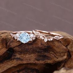 an engagement ring with blue topazte and white diamond accents on a piece of wood