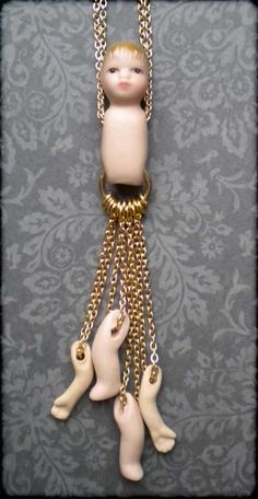 a small doll hanging from a chain with two smaller dolls attached to it's sides