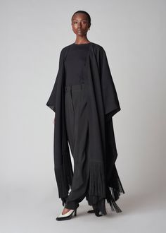 Full length dramatic woven cape trimmed with black fringe. Fused lining. One size. Details 100% Viscose Black 9163RBV-F24 One size Approx 28" in length (front) 33" length (back Model is 5'10" Fringe Shawl Cape For Fall, Fall Shawl Cape With Fringe, Oversized Fringe Casual Poncho, Black Oversized Chic Poncho, Luxury Oversized Black Poncho, Elegant Black Fringe Outerwear, Black Bohemian Handwoven Poncho, Luxury Fringe Winter Poncho, Black Fringe Poncho Shawl