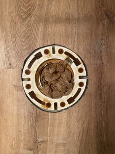 an overhead view of a bowl with food in it on a wooden surface, looking down at the ground