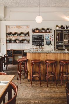 an empty bar with stools and bottles on the wall