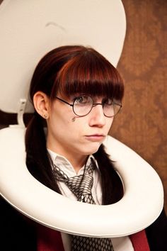 a woman wearing glasses and a neck tie with a toilet seat cover on her head