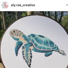 a close up of a embroidery on a piece of cloth with an image of a sea turtle