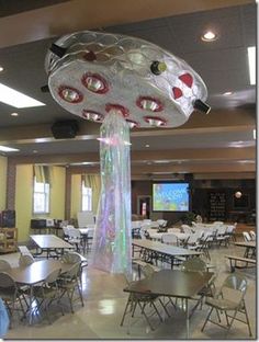 a room filled with tables and chairs next to a projector screen in the ceiling