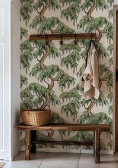 a bench and coat rack in front of a wallpapered entryway with trees on it