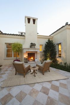 an outdoor living area with two chairs and a fire place in the middle of it