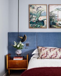 a bed with two paintings above it and a night stand next to the headboard