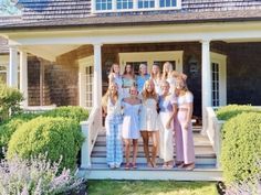 a group of women standing on the steps of a house in front of some bushes