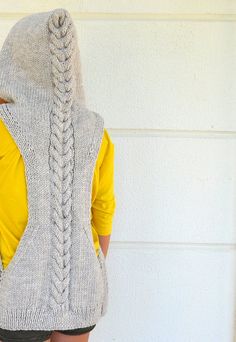 a woman wearing a sweater with braids on the back and yellow shirt behind her