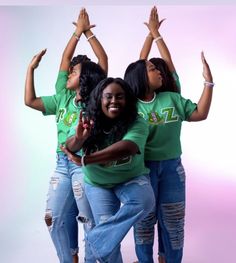 three women in green shirts and jeans are posing for the camera with their hands up