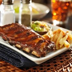 ribs and french fries are served on a white plate