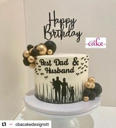 a white and black birthday cake with gold decorations on it's side, sitting on top of a table