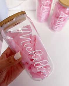 a person holding a jar with pink tissue in it and two bottles behind them that say love