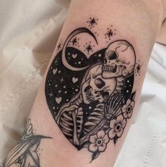 a tattoo on the arm of a person with a heart shaped skull and flowers in it