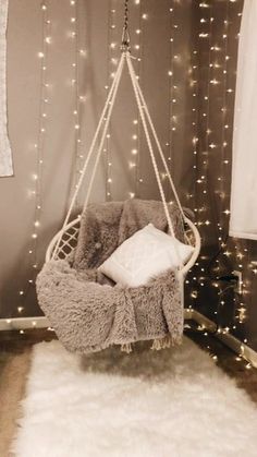 a hanging chair in the corner of a room with christmas lights on the wall behind it