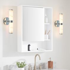 a bathroom vanity with two lights on the wall and a mirror above it that is open