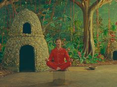 a man sitting on top of a cement block in front of a forest filled with trees