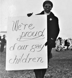 an old black and white photo of a woman holding a sign that says we're proud of our gay children