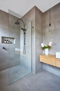 a bathroom with a glass shower door, sink and flowers in the vase on the counter