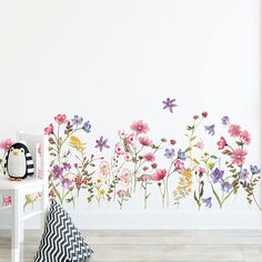 a wall with flowers painted on it and a black and white chair in the foreground