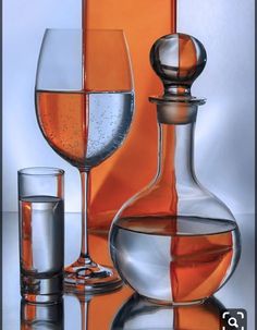 two wine glasses and a decanter on a reflective surface