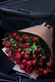 a bunch of flowers that are sitting in the back seat of a car with paper wrapped around it