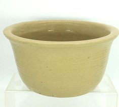 a large brown bowl sitting on top of a clear stand with a white background behind it