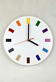 a white clock with multicolored squares on it's face and numbers in the middle