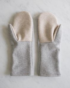 two gray mittens sitting on top of a white marble counter next to each other