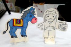 two paper cutouts of people and a horse on a table