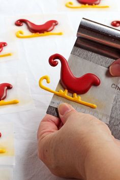 someone is cutting out red and yellow plastic animals