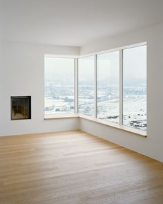 an empty room with large windows and a fire place