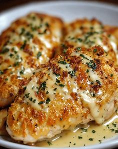 three pieces of chicken covered in gravy on a white plate with parsley