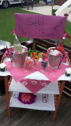 a pink table topped with buckets filled with food and drinks next to a sign that says sekt - a - bar