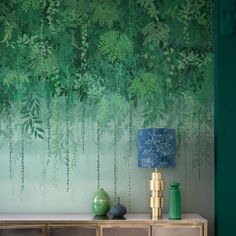 a wall with green leaves painted on it and two vases sitting on the sideboard