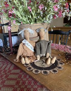 two stuffed animals sitting on top of a wooden table next to a potted plant