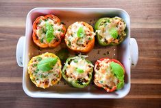 several stuffed peppers in a white casserole dish on a wooden table with parsley