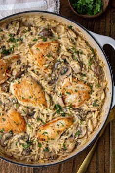 chicken and mushroom pasta in a skillet on a wooden table