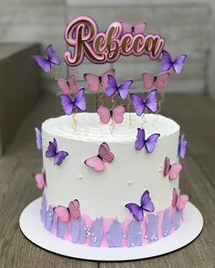 a white cake with pink and purple butterflies on it that says reebo above the top