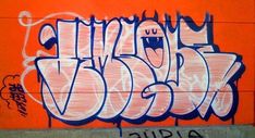 an orange wall with some graffiti on it