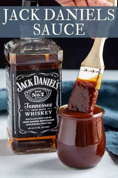 a jar filled with jack daniels sauce next to a wooden spoon