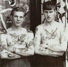 two men with tattoos standing next to each other